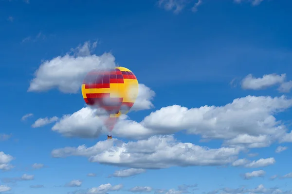 Varm luft färgglada ballon mot blå himmel med vita fluffiga moln — Stockfoto