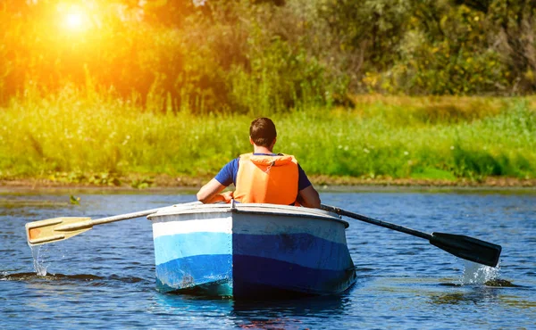 Mann in Schwimmweste rudert mit Boot über klares Wasser auf dem Fluss i — Stockfoto