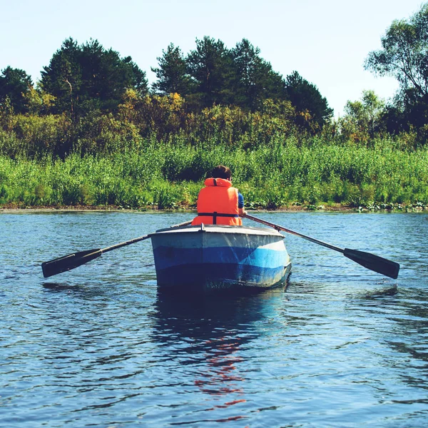 Homem de colete salva-vidas remando um barco sobre água limpa no rio , — Fotografia de Stock