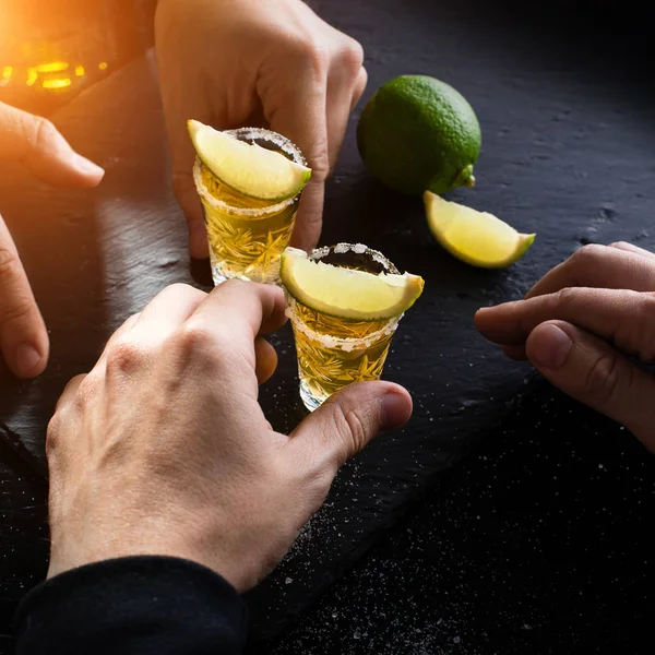 Dos mexicanos en el bar bebiendo un trago de tequila dorado con lima —  Fotos de Stock