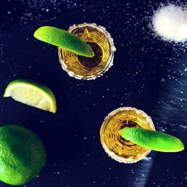 Tequila mexicana dorada con lima y sal sobre mesa oscura. Vista superior , —  Fotos de Stock