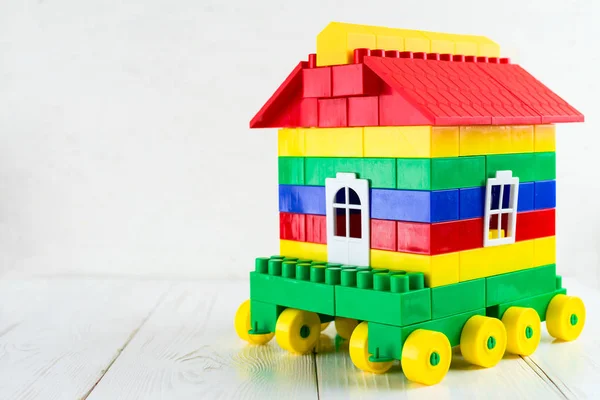 Barevná hračka dům na kolech na světlé pozadí. Koncept mov — Stock fotografie