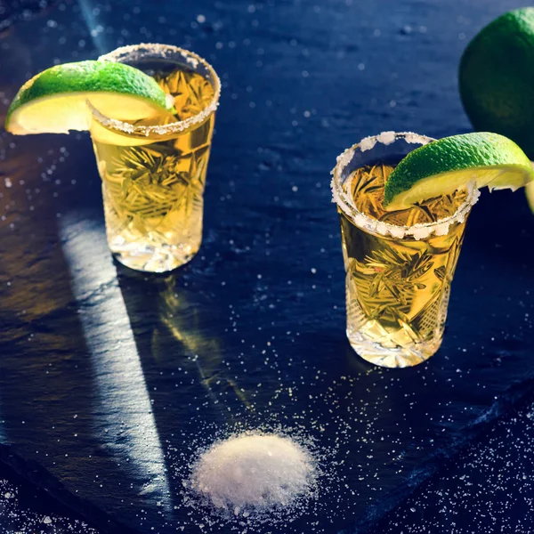 Tequila mexicana dorada con lima y sal sobre mesa oscura, tonificada ima —  Fotos de Stock