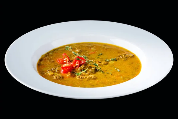 Sopa de pimenta saborosa com manjericão em uma placa branca isolada em ba escuro — Fotografia de Stock