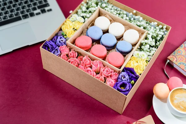 Box with beautiful colorful flowers and macaroons