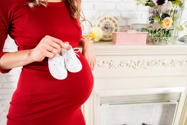 Femme enceinte non identifiée tenant une paire de bottines blanches — Photo
