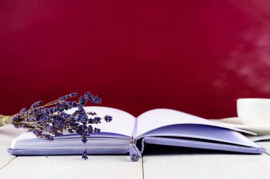 Mor defter, fincan kahve ve hafif ahşap backg çiçekler