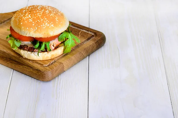 Heerlijke smakelijke hamburger met rundvlees, tomaten, salade en saus op l — Stockfoto