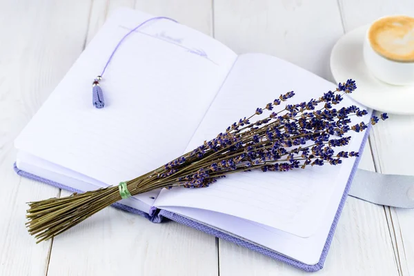 Mor defter, fincan kahve ve hafif ahşap backg çiçekler