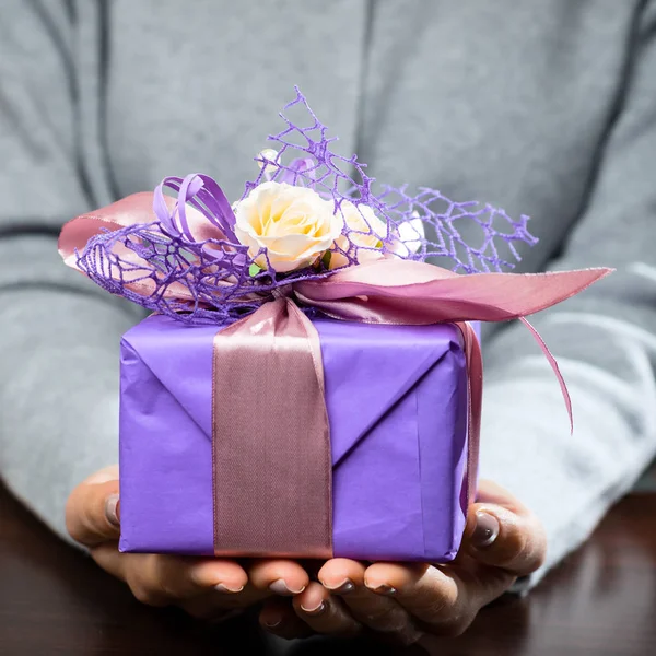 Pequeña caja de regalo púrpura con cinta en manos de mujer . — Foto de Stock