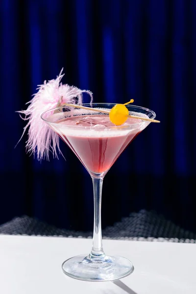 Coquetel rosa alcoólico em um copo de martini com palha em azul ba — Fotografia de Stock