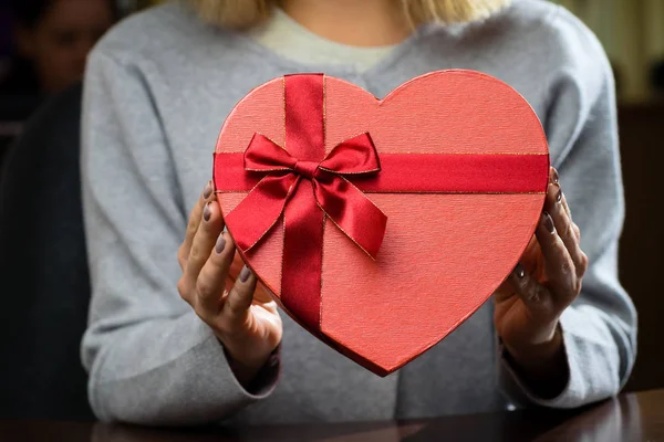 Caja de regalo roja con cinta en forma de corazón en manos de mujer. F — Foto de Stock