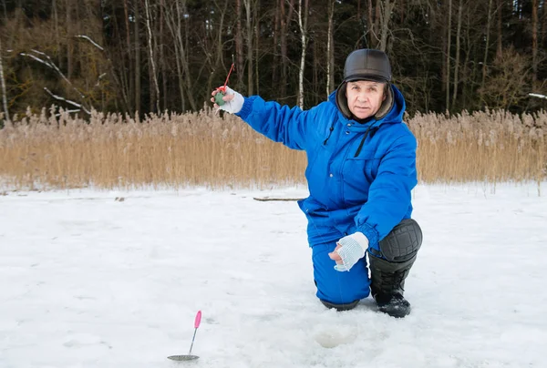 Yaşlı adam soğuk kış gününde gölde balık tutma