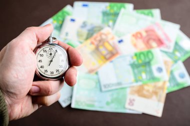 Farklı euro banknot o yığın karşı adam elinde kronometre