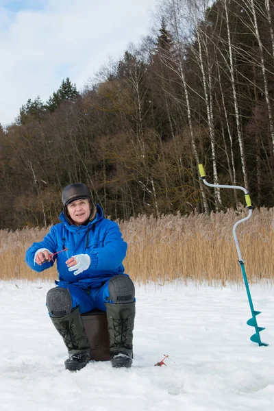 Первопроходец ловит рыбу на озере в зимний холодный день — стоковое фото