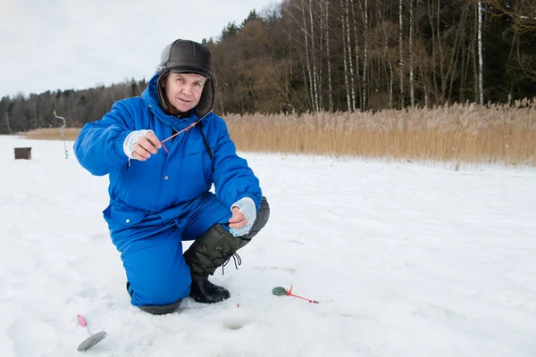 Yaşlı adam soğuk kış gününde gölde balık tutma