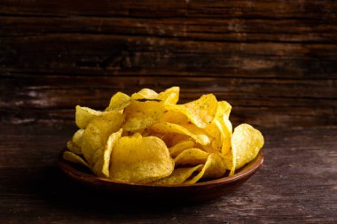 Gevrek tuzlu lezzetli patates cipsi karanlık ahşap plaka 