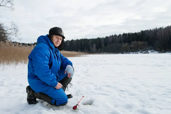 Старик рыбачит на озере в холодный зимний день — стоковое фото