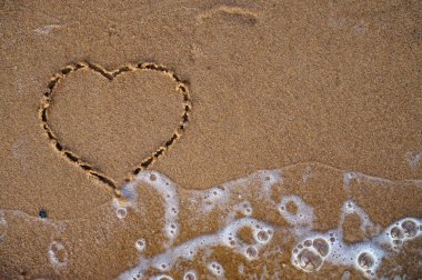 Üstten görünüm kum plaj deniz dalgası ile çizilmiş kalp. BEAC