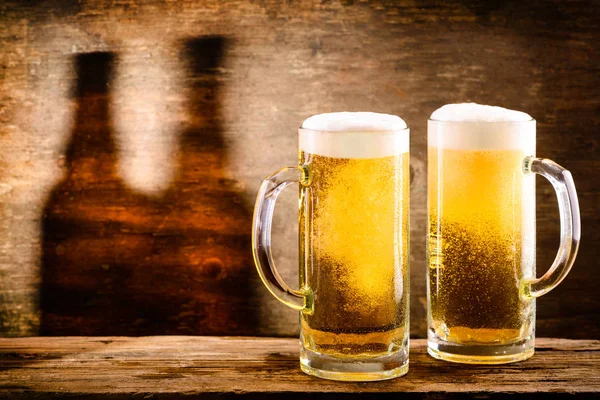 Two fresh cold light beer in a beer mug with foam and drops of w