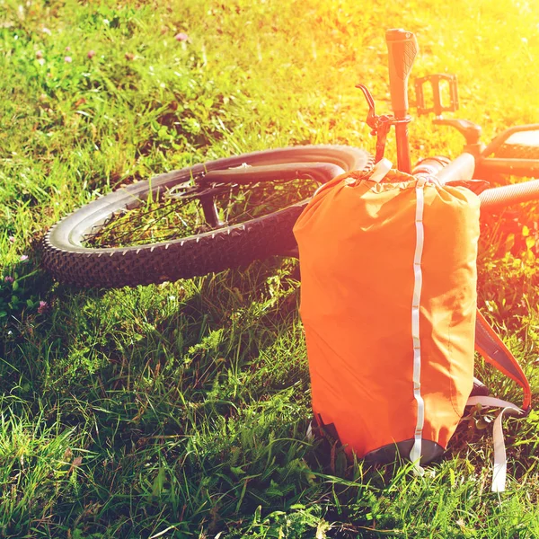 Fahrrad und Rucksack liegen auf grünem Gras im Park — Stockfoto