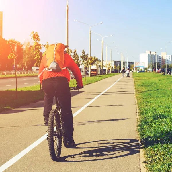 Vista posteriore dell'uomo adulto con zaino in sella ad una bicicletta in cit — Foto Stock