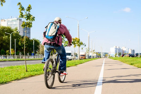 Bakifrån av vuxen man med ryggsäck rider en cykel i cit — Stockfoto