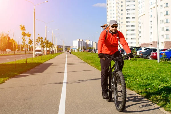 Взрослый мужчина с рюкзаком на велосипеде на городской улице. Автомобиль — стоковое фото