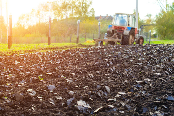 Tractor plowing a land in rays of the sun, rural life in Russia.