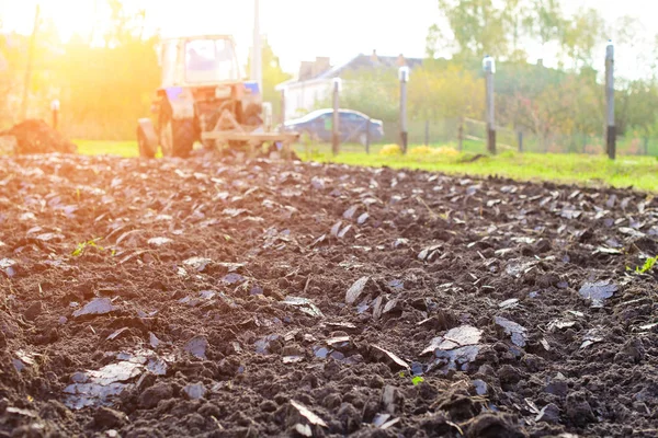 Traktor pflügt Land in Sonnenstrahlen, ländliches Leben in Russland. — Stockfoto