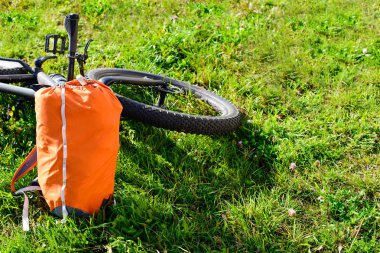 Bisiklet ve sırt çantası parkta güneşli bir günde yeşil çim üzerinde yalan
