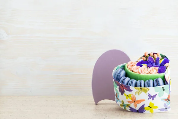 Caja-corazón con flores y macarrones sobre un fondo de madera. Policía. — Foto de Stock