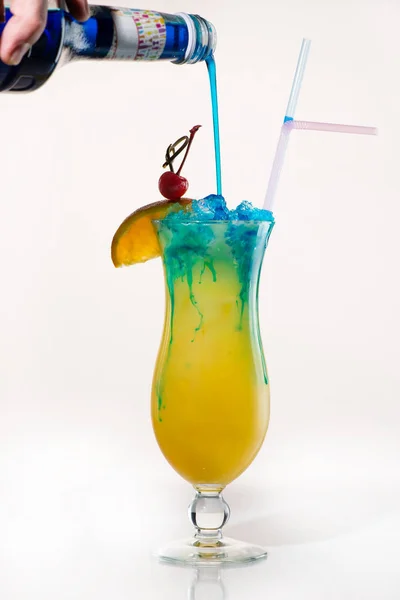 Vorbereitung eines exotischen Cocktails, um blauen Sirup in Orangensaft zu gießen — Stockfoto