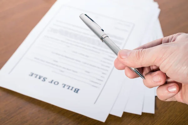 Mans hand with a pen gives pen for signing a contract Stock Picture