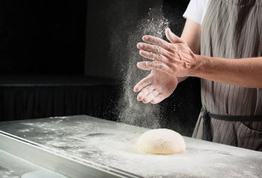 kadın baker rulo hamur ahşap oyun tahtası üzerinde un serpilir. Pro