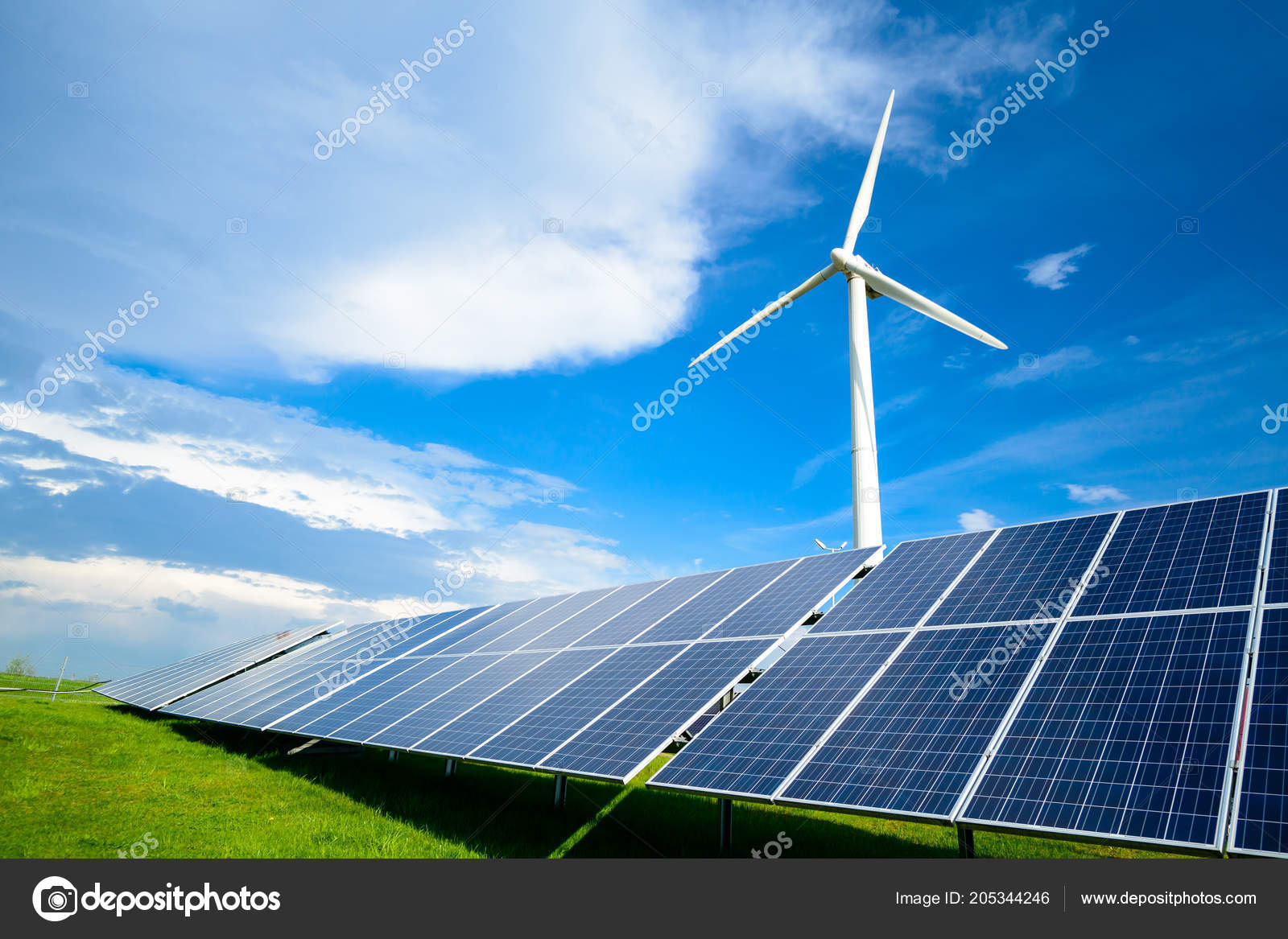Solar energy panels and windmills against blue sky on summer day Stock