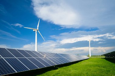 Güneş enerjisi panelleri ve mavi gökyüzü yaz gününde karşı yel değirmenleri