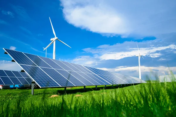 Солнечные батареи и ветряные мельницы против голубого неба в летний день — стоковое фото
