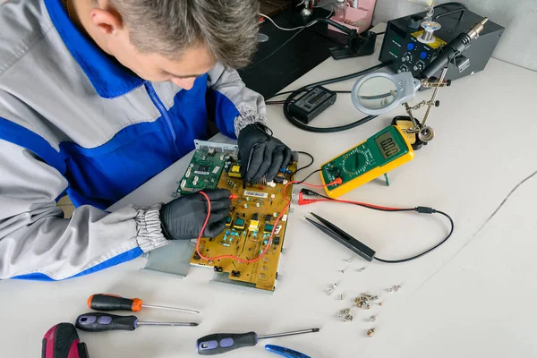 Master is looking for damage, repair office equipment using a multimeter.