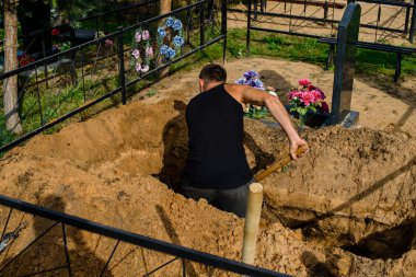 grave-digger digs a grave, a man digs a grave with a shovel in a cemetery clipart