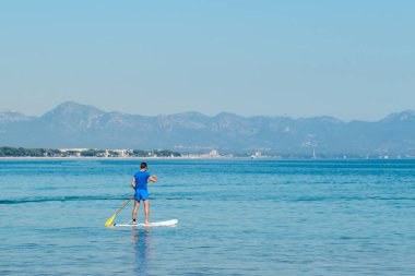 Yatılı, kürek Sup tahta, macera deniz bir sörf üzerinde mavi su üzerinde yüzen geri adam ayağa