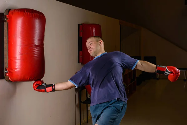 novice male boxer training with punching bag on dark background. Male boxer as exercise for the big fight.