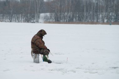 balıkçı kışın buz deliği balık yakalar