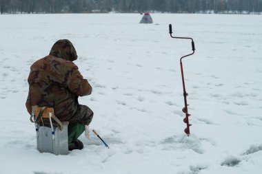balıkçı kışın buz deliği balık yakalar