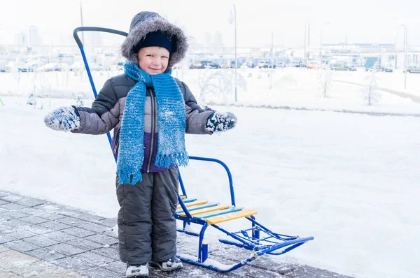Fröhlicher Junge Winter Auf Einem Schlitten Gegen Einen Weißen Schneeschlitten — Stockfoto