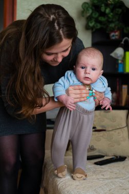 Bebek annesiyle yürümeyi öğreniyor, anne bebeğe yürümeyi öğretiyor.