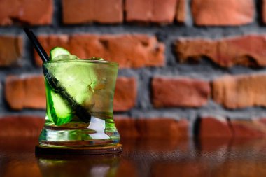 Salatalık kokteyli tezgahın üzerinde fotokopi alanı, salatalıklı cin tonik kokteyli ve karanlık arka plandaki ahşap tepside buz.