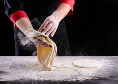 Şefin elleri ahşap arka planda hamur pişiriyor. Yemek konsepti. Pizza yapan adam.