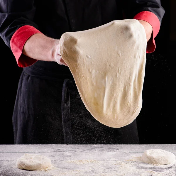 Chef hands cooking dough on dark wooden background. Food concept. Man making pizza dough