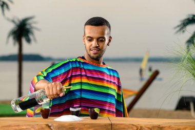 Meksikalı barmen sahilde tekila ve tuz kokteyli yapar.